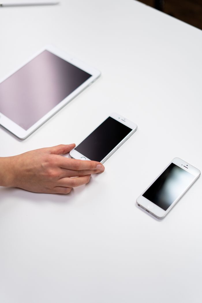 who-we-are Top view of a minimalist setup featuring a tablet and smartphones on a white surface.